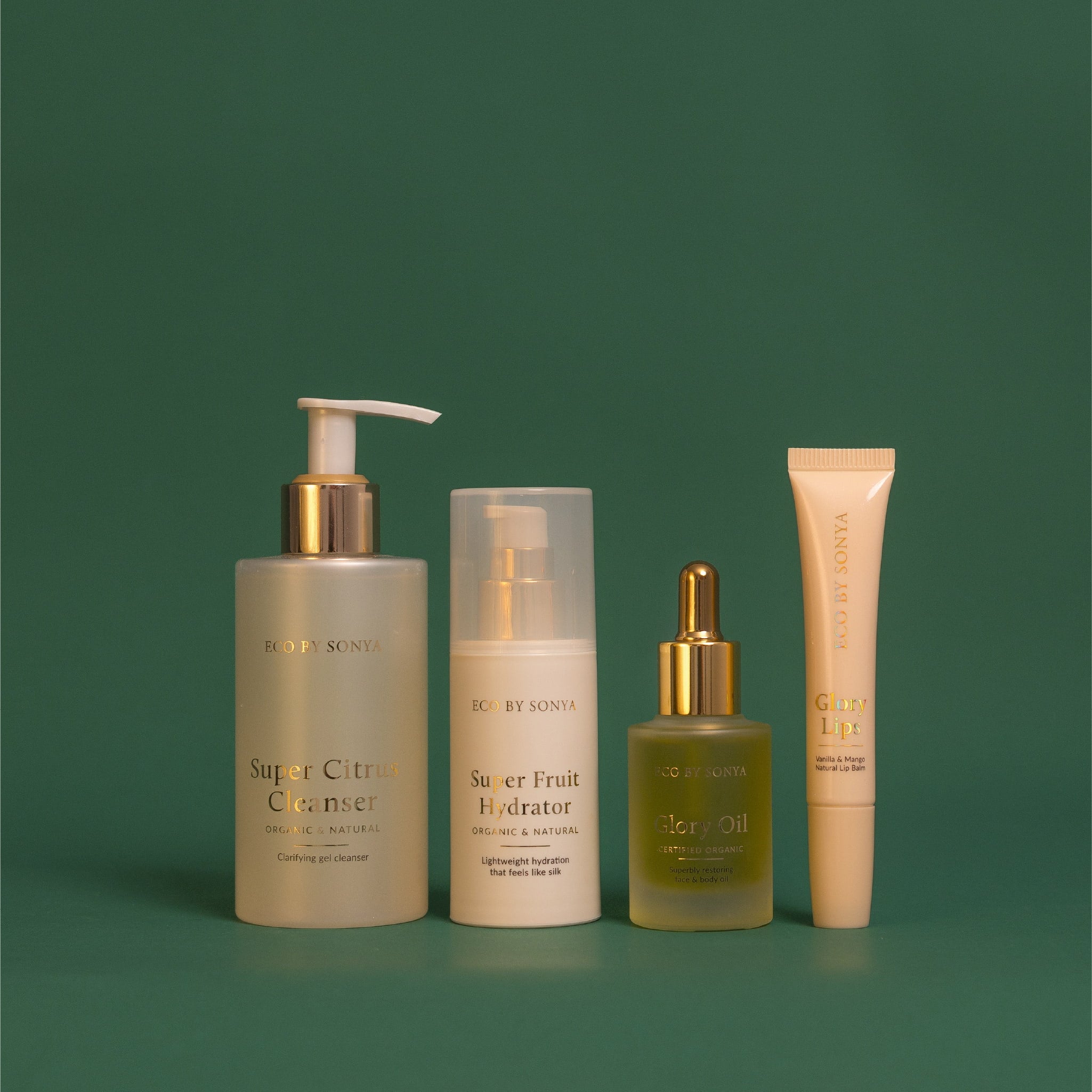Eco By Sonya The Christmas Staples Gift Set featuring Super Citrus Cleanser, Super Fruit Hydrator, Glory Oil and bonus Glory Lips arranged in a line.